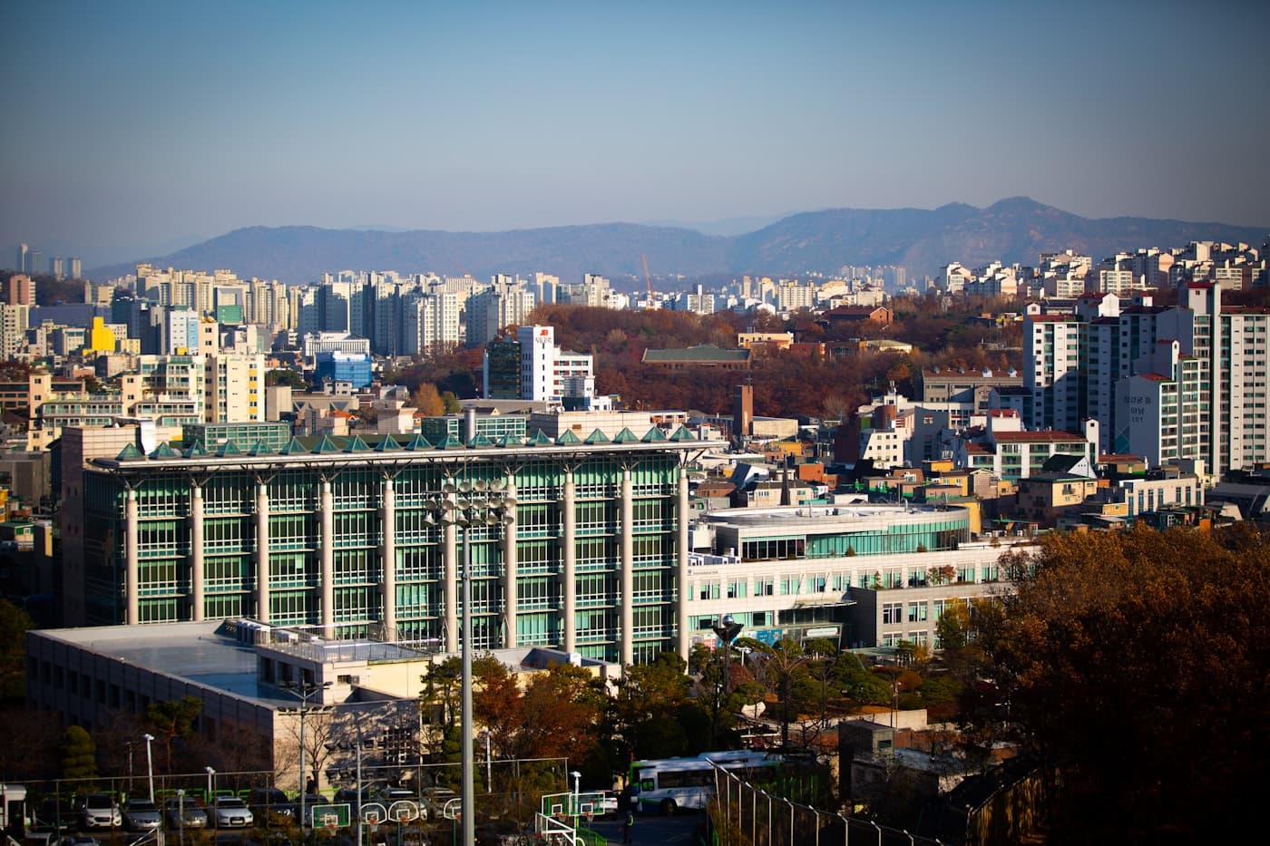 Contemporary campus buildings against a Korean city skyline